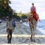 A tourist rides on a camel's back at the Jomo Kenyatta public beach in Kenya's coastal city of Mombasa, March 24, 2013. Kenya's tourism industry may be a swift winner from the election of Uhuru Kenyatta, owner of hotels and a vast business empire, as east Africa's biggest economy seeks to benefit from a vote that avoided a re-run of bloodshed of five years ago. Picture taken March 24, 2013. To match story KENYA-ECONOMY/TOURISM REUTERS/Joseph Okanga (KENYA - Tags: TRAVEL POLITICS BUSINESS ANIMALS)
