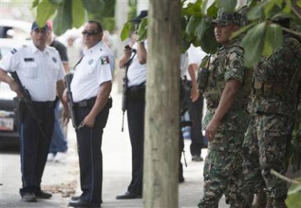 Soldiers (R) and police officers stand guard at a crime scene where six people were strangled to death and one decapitated in a shack in the outskirts of Cancun April 14, 2013. Police found the bodies of the five men and two women in a shack in the outskirts of Cancun, a major tourist destination on Mexico's Caribbean coast, that has largely escaped the drug-related violence that has racked Acapulco, a faded tourist hot spot on the Pacific coast. REUTERS/Victor Ruiz Garcia