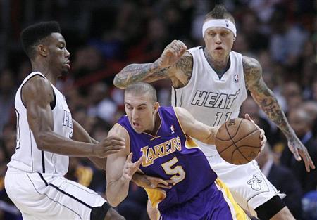 Miami Heat's Norris Cole (L) defends against Los Angeles Lakers' Steve Blake (C) as Heat teammate Chris Andersen (R) looks on in the first half of their NBA basketball game in Miami, Florida February 10, 2013. REUTERS/Andrew Innerarity
