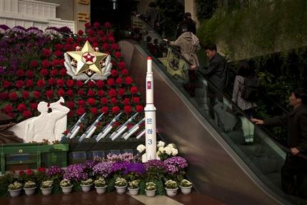 People visit a flower show featuring thousands of Kimilsungia flowers, named after the late leader Kim Il Sung, while models of a rocket and missiles are also displayed in Pyongyang, North Korea, Friday, April 12, 2013. (AP Photo/Alexander F. Yuan)