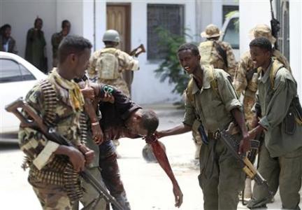 Somali soldiers help an injured civilian near the scene of a deadly blast in Mogadishu April 14, 2013. REUTERS/Feisal Omar