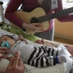 Music therapist Elizabeth Klinger, right, quietly plays guitar and sings for Augustin as he grips the hand of his mother, Lucy Morales, in the newborn intensive care unit at Ann & Robert H. Lurie Children's Hospital in Chicago on Monday, May 6, 2013. Research suggests that music may help those born way too soon adapt to life outside the womb. Recent studies and anecdotal reports suggest the vibrations and soothing rhythms of music, especially performed live in the hospital, might benefit preemies and other sick babies. (AP Photo/M. Spencer Green)