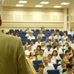 A man stands in front of a crowd in a lecture hall.