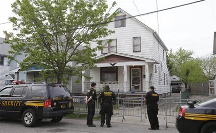 Sheriff deputies stand outside a house in Cleveland Tuesday, May 7, 2013, the day after three women who vanished a decade ago were found there. Amanda Berry, Gina DeJesus and Michelle Knight, who went missing separately about a decade ago, were found in the home just south of downtown Cleveland and likely had been tied up during years of captivity, said police, who arrested three brothers. (AP Photo/Tony Dejak)