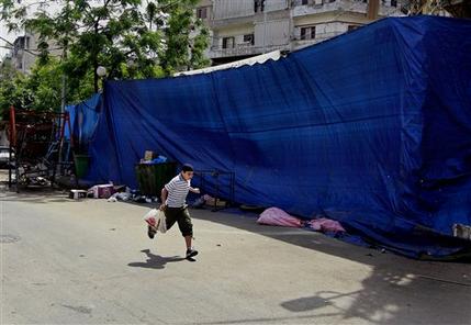 In this Friday, May 24, 2013 photo, a Lebanese boy runs for cover, during clashes that erupted between supporters and opponents of the Syrian regime, in the northern port city of Tripoli, Lebanon. Fighting between Bab Tabbaneh and Jabal Mohsen, which goes back to Lebanon's civil war, has become more frequent since the start of the Syrian conflict in 2011, with the neighborhoods backing opposite sides. And the latest round over the past week has been the longest yet and has left tens dead and hundreds wounded, the highest toll so far. (AP Photo/Bilal Hussein)