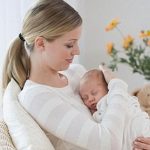 Mother rocking newborn baby in chair