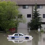 A police car sits stuck in a parking lot of an apartment building after heavy rains have caused flooding, closed roads, and forced evacuation in Calgary, Alberta, Canada Friday, June 21, 2013. (AP Photo/The Canadian Press, Jeff McIntosh)