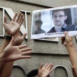 A supporter holds a picture of Edward Snowden, a former CIA employee who leaked top-secret information about U.S. surveillance programs, outside the U.S. Consulate General in Hong Kong Thursday, June 13, 2013. The news of Snowden's whereabouts, revealed by an editor of a local newspaper that interviewed him Wednesday, is the first since he went to ground Monday after checking out of his hotel in this autonomous Chinese territory. (AP Photo/Kin Cheung)