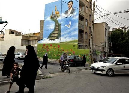 In this Tuesday, May 28, 2013 photo, Iranian pedestrians make their way, under a mural showing Ali Asghar Dehnadi, who was killed during 1980-88 Iran-Iraq war, in downtown Tehran, Iran. On the roughneck streets in south Tehran, paramilitary volunteers look to the most hard-line presidential candidate as the best defender of the Islamic system. On the other end of Tehran's social ladder, a university professor plans to snub next week's election. In between is a mix of splintered views, apathy and indecision based on dozens of AP interviews suggesting a still wide open race. (AP Photo/Vahid Salemi)