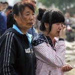 In this June 3, 2013 photo released by China's Xinhua News Agency, a family member of a worker cries as she waits for information after a fire occurred in a slaughterhouse owned by the Jilin Baoyuanfeng Poultry Company in Mishazi Township of Dehui City, northeast China's Jilin Province. A swift-moving fire trapped panicked workers inside the poultry slaughterhouse that had only a single open exit, killing at least 119 people in one of the country's worst industrial disasters in years. (AP Photo/Xinhua, Wang Haofei) NO SALES