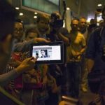 Journalists show passengers arriving from Hong Kong a tablet with a photo of Edward Snowden, a former CIA employee who leaked top-secret documents about sweeping U.S. surveillance programs, at Sheremetyevo airport, just outside Moscow, Russia, Sunday, June 23, 2013. The former National Security Agency contractor wanted by the United States for revealing two highly classified surveillance programs has been allowed to leave for a "third country" because a U.S. extradition request did not fully comply with Hong Kong law, the territory's government said Sunday. (AP Photo/Alexander Zemlianichenko)