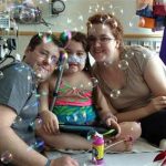 FILE - In this May 30, 2013 file photo provided by the Murnaghan family, Sarah Murnaghan, center, celebrates the 100th day of her stay in Children's Hospital of Philadelphia with her father, Fran, left, and mother, Janet. A federal judge in Philadelphia on Wednesday, June 5, 2013 made the dying 10-year-old eligible to seek donor lungs from an adult transplant list. (AP Photo/Murnaghan Family, File)