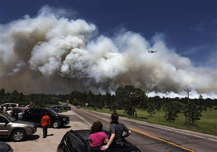 People pulled to over watch from their cars as a fire-fighting slurry plane makes a pass in preparation to drop its load on a wildfire in the Black Forest area north of Colorado Springs, Colo., on Wednesday, June 12, 2013. The number of houses destroyed by the Black Forest fire could grow to around 100, and authorities fear it's possible that some people who stayed behind might have died. (AP Photo/Brennan Linsley)