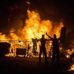 Protesters gesture to riot police as they stand in front of a burning barricade during an anti-government protest in Rio de Janeiro, Brazil, Thursday, June 20, 2013. More than half a million Brazilians poured into the streets of at least 80 Brazilian cities Thursday in demonstrations that saw violent clashes and renewed calls for an end to government corruption and demands for better public services. Riot police battled protesters in at least five cities, with some of the most intense clashes happening in Rio de Janeiro, where an estimated 300,000 demonstrators swarmed into the seaside city's central area. (AP Photo/Victor R. Caivano)