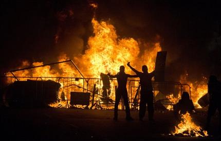 Protesters gesture to riot police as they stand in front of a burning barricade during an anti-government protest in Rio de Janeiro, Brazil, Thursday, June 20, 2013. More than half a million Brazilians poured into the streets of at least 80 Brazilian cities Thursday in demonstrations that saw violent clashes and renewed calls for an end to government corruption and demands for better public services. Riot police battled protesters in at least five cities, with some of the most intense clashes happening in Rio de Janeiro, where an estimated 300,000 demonstrators swarmed into the seaside city's central area. (AP Photo/Victor R. Caivano)