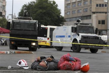 Protesters sleep on the marbles of Taksim Square near police water cannon trucks in Istanbul early Friday, June 14, 2013. A meeting between Turkey's Prime Minister Recep Tayyip Erogan and representatives of anti-government protesters ended early Friday without a clear resolution on how to end the occupation of a central Istanbul park that has become a flashpoint for the largest political crisis of his 10-year rule (AP Photo/Thanassis Stavrakis)