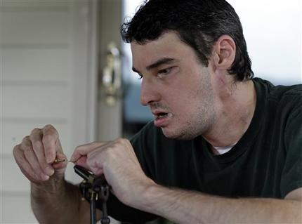 In this photo taken July 25, 2013 Richard Norris ties a fishing fly at his home in Hillsville, Va. The man whose face was disfigured by a gunshot spent 15 years as a recluse, but now the 37-year-old is doing things he never would have before. (AP Photo/Chuck Burton)