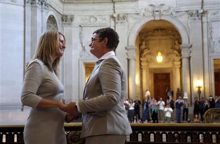 Sandy Stier, left, exchanges wedding vows with Kris Perry during a ceremony presided by California Attorney General Kamala Harris at City Hall in San Francisco, Friday,  June 28, 2013. Stier and Perry, the lead plaintiffs in the U.S. Supreme Court case that overturned California's same-sex marriage ban, tied the knot about an hour after a federal appeals court freed same-sex couples to obtain marriage licenses for the first time in 4 1/2 years. (AP Photo/Marcio Jose Sanchez)