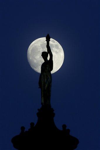 The moon in its waxing gibbous stage shines behind a statue entitled "Enlightenment Giving Power" by John Gelert, which sits at the top of the dome of the Bergen County Courthouse in Hackensack, N.J., Friday, June 21, 2013. The moon, which will reach its full stage on Sunday, is expected to be 13.5 percent closer to earth during a phenomenon known as supermoon. (AP Photo/Julio Cortez)