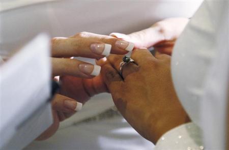 A woman puts a ring on the hand of another woman in a civil union ceremony after Colorado's civil union law went into effect in Denver May 1, 2013. REUTERS/Rick Wilking