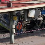 A railway worker walks next to a train which derailed at a station in Bretigny-sur-Orge, south of Paris, Saturday, July 13, 2013. An official on Saturday said a faulty rail joint may have caused a train derailment outside Paris that left six people dead and injured dozens. (AP Photo/Thibault Camus)