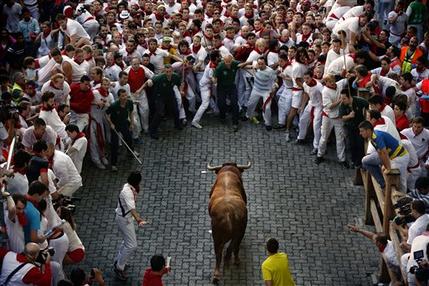 An Alcurrucen's ranch fighting bull runs towards revelers during the running of the bulls of the San Fermin festival, in Pamplona, Spain, Sunday, July 7, 2013. Revelers from around the world arrive to Pamplona every year to take part on some of the eight days of the running of the bulls glorified by Ernest Hemingway's 1926 novel "The Sun Also Rises." (AP Photo/Daniel Ochoa de Olza)