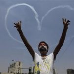 An Egyptian protester flashes v signs for military aircrafts forming a heart shape trails in the sky over Tahrir Square in Cairo, Egypt, Friday, July 5, 2013. Egypt's Muslim Brotherhood called for a wave of protests Friday, furious over the military's ouster of its president and arrest of its revered leader and other top figures, underlining the touchy issue of what role the fundamentalist Islamist movement might play in the new regime. (AP Photo/Amr Nabil)