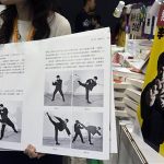 A shopkeeper introduces a latest Chinese edition of "Bruce Lee's Fighting Method" by the late Kung Fu legend Bruce Lee on the first day of the week-long Hong Kong Book Fair July 17, 2013. July 20 marks the 40th anniversary of the Lee's death, with memorial events to be held by his fans in the territory. REUTERS/Tyrone Siu
