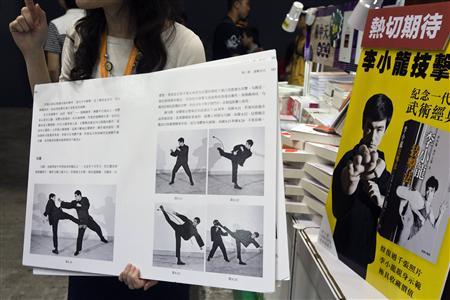 A shopkeeper introduces a latest Chinese edition of "Bruce Lee's Fighting Method" by the late Kung Fu legend Bruce Lee on the first day of the week-long Hong Kong Book Fair July 17, 2013. July 20 marks the 40th anniversary of the Lee's death, with memorial events to be held by his fans in the territory. REUTERS/Tyrone Siu