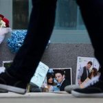 A pedestrian walks past photographs and flowers placed at a memorial for Canadian actor Cory Monteith outside the Fairmont Pacific Rim Hotel in Vancouver, British Columbia on Monday, July 15, 2013. Monteith, 31, was found dead in his room at the hotel on Saturday, according to police, who have ruled out foul play. (AP Photo/The Canadian Press, Darryl Dyck)