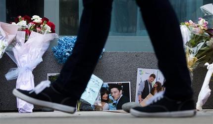 A pedestrian walks past photographs and flowers placed at a memorial for Canadian actor Cory Monteith outside the Fairmont Pacific Rim Hotel in Vancouver, British Columbia on Monday, July 15, 2013. Monteith, 31, was found dead in his room at the hotel on Saturday, according to police, who have ruled out foul play. (AP Photo/The Canadian Press, Darryl Dyck)