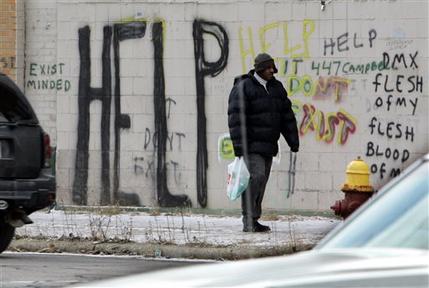 FILE - In a Dec. 12, 2008 file photo, a pedestrian walks by graffiti in downtown Detroit. On Thursday, July 18, 2013 Detroit became the largest city in U.S. history to file for bankruptcy when State-appointed emergency manager Kevyn Orr asked a federal judge for municipal bankruptcy protection. (AP Photo/Carlos Osorio, FILE)