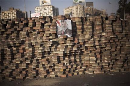 A picture of Egypt's ousted President Mohammed Morsi is displayed on a makeshift barricade in Nasr City, where protesters have installed a camp and hold daily rallies, in Cairo, Monday, July 29, 2013.  Europe's top diplomat urged Egypt's government to reach out to the Muslim Brotherhood as she worked Monday to mediate an end to the country's increasingly bloody crisis, while the mainly Islamist protesters calling for the return of ousted leader Mohammed Morsi massed for more protests. (AP Photo/Manu Brabo)