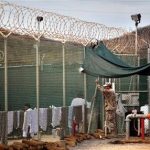 FILE - In this Jan. 21, 2009, file photo, reviewed by the U.S. Military, a guard talks to a Guantanamo detainee in the open yard in Camp 4 detention center on the U.S. Naval Base in Guantanamo Bay, Cuba. President Barack Obama's renewed push to close the Guantanamo Bay prison for terrorism suspects has given a glimmer of hope to foreign governments that he will fulfill that promise and triggered diplomatic maneuvering from U.S. allies eager to bring home long-held detainees, some badly ailing from a hunger strike to protest their confinement. (AP Photo/Brennan Linsley, File)