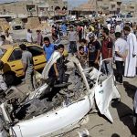 Iraqis inspect the aftermath of a car bomb attack