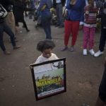 South African Amonra Maluleka, 2, holds a framed picture showing former South African President Nelson Mandela, at the entrance to the Mediclinic Heart Hospital where Mandela is being treated in Pretoria, South Africa, Tuesday, July 9, 2013. Grandson Ndaba Mandela said Tuesday that the ailing former president is very much alive and urged well-wishers to celebrate the life of the anti-apartheid leader ahead of his 95th birthday. (AP Photo/Muhammed Muheisen)