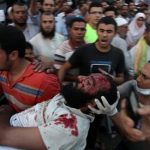 Supporters of Egypt's ousted President Mohammed Morsi carry an injured man to a field hospital following clashes with security forces at Nasr City, where pro-Morsi protesters have held a weekslong sit-in, in Cairo, Egypt, Saturday, July 27, 2013. Police fired tear gas to disperse hundreds of Morsi supporters, setting off clashes that lasted for hours and left tens of people dead. (AP Photo/Khalil Hamra)