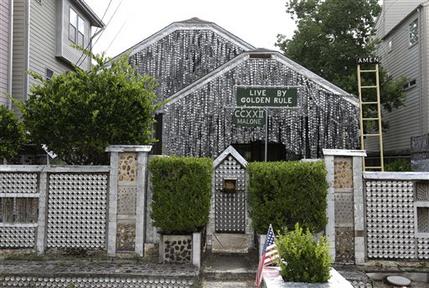 The beer can house, a Houston landmark, sits between newer homes Wednesday, July 10, 2013, in Houston. Former owner John Milkovisch covered the outside on the house with siding made of cut and flatten beer cans and garlands made from the lids. The Orange Show Center for Visionary Art, a local nonprofit that preserves art installations in the city, bought the property about 10 years ago, restored the house and it opened it to the public. (AP Photo/Pat Sullivan)