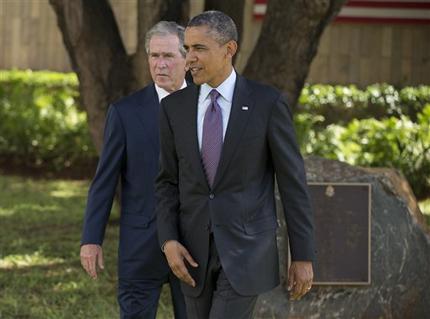 U.S. President Barack Obama, right, and former U.S. president George W. Bush walk to meet with family members of the U.S. embassy victims during a wreath laying ceremony to honor the victims of the U.S. Embassy bombing on Tuesday, July 2, 2013, in Dar Es Salaam, Tanzania. The president is traveling in Tanzania on the final leg of his three-country tour in Africa. (AP Photo/Evan Vucci)