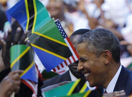U.S. President Barack Obama is surrounded by Tanzanian and United States flags while greeting people at an official arrival ceremony in Dar Es Salaam July 1, 2013. REUTERS/Gary Cameron
