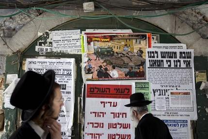 In this Sunday, July 14, 2013 photo, ultra-Orthodox Jewish men walk past a poster in the ultra-Orthodox Jewish Mea Shearim neighborhood in Jerusalem. A large cartoon poster depicts Haredi soldiers rolling through the streets atop tanks trying to lure young boys onto their vehicles. The ad denounces the soldiers as Zionist "ambassadors" and "missionaries." The soldiers in sidecurls have been coined the insulting nickname "Hardak" _ a combination of Haredi and insect. (AP Photo/Sebastian Scheiner)