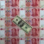 A U.S. $100 banknote is placed on top of 100 yuan banknotes in this picture illustration taken in Beijing