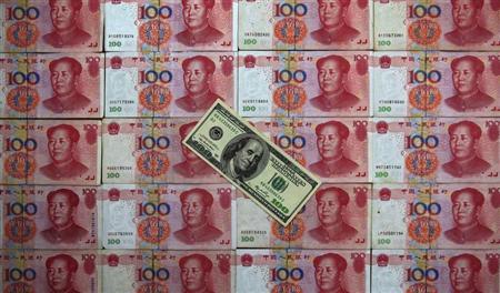 A U.S. $100 banknote is placed on top of 100 yuan banknotes in this picture illustration taken in Beijing