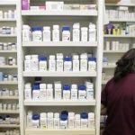 A pharmacy employee looks for medication as she works to fill a prescription while working at a pharmacy in New York
