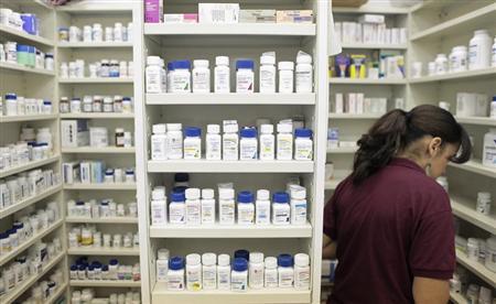 A pharmacy employee looks for medication as she works to fill a prescription while working at a pharmacy in New York