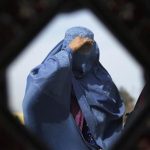 An Afghan woman is reflected in a mirror as she walks in Kabul