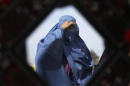 An Afghan woman is reflected in a mirror as she walks in Kabul
