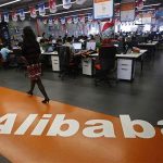 File photo of an employee walking past a logo of Alibaba Group at its headquarters on the outskirts of Hangzhou