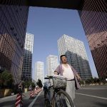 A news vendor walks with a bicycle at the Central Business District in Beijing