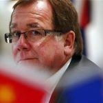 New Zealand Foreign Minister Murray McCully is seen behind Chinese and New Zealand flags during a group interview in Beijing